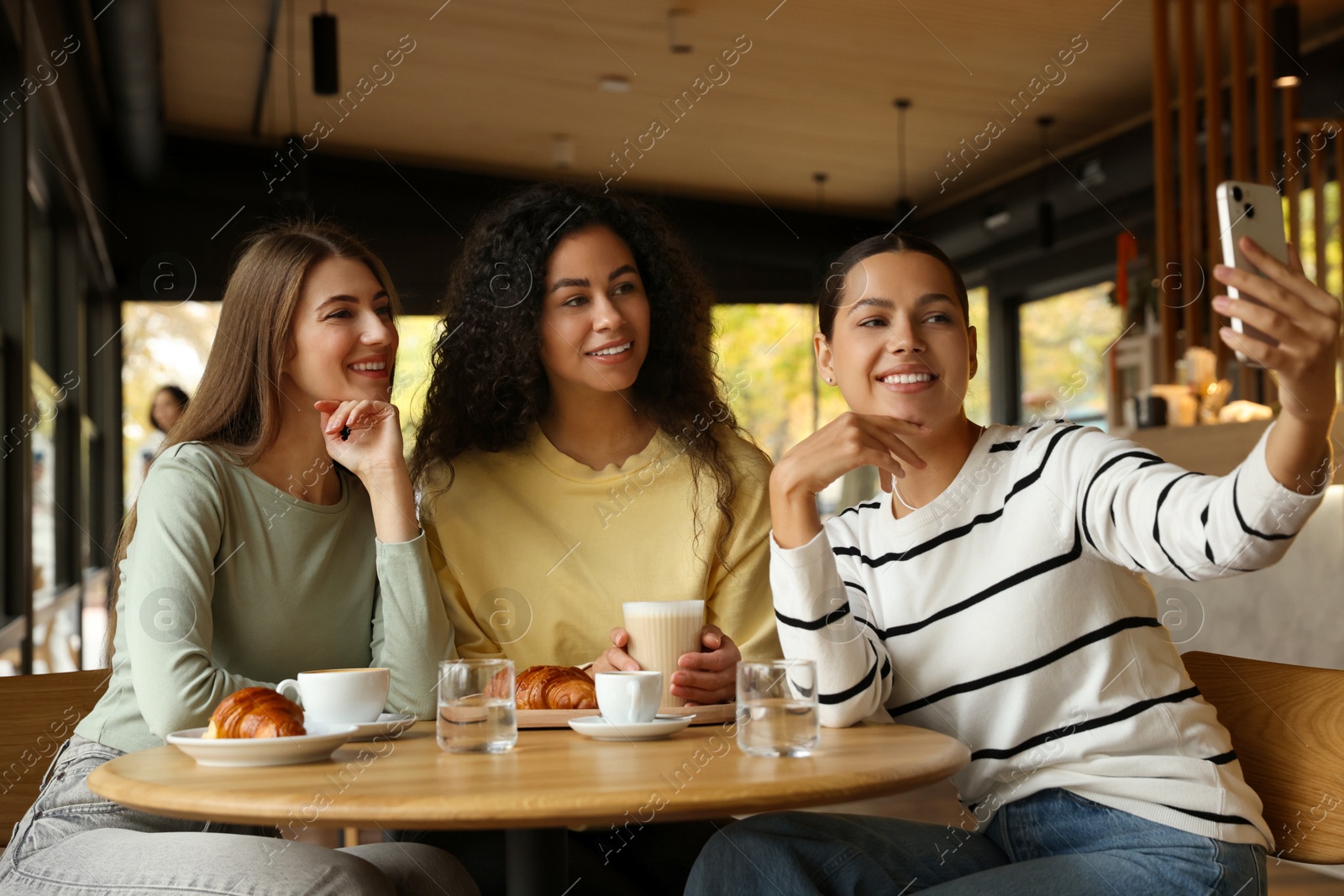 Photo of Happy friends taking selfie during coffee meeting in cafe