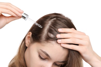 Photo of Hair loss problem. Girl applying serum onto hairline on white background, closeup