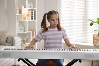 Photo of Cute girl playing synthesizer at home. Electronic musical instrument