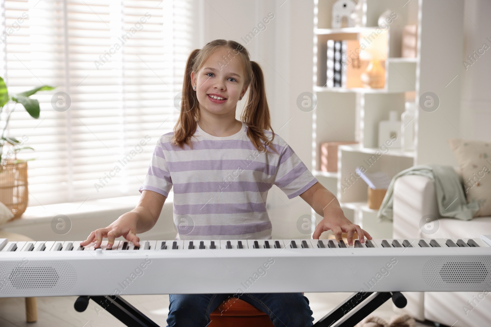 Photo of Cute girl playing synthesizer at home. Electronic musical instrument