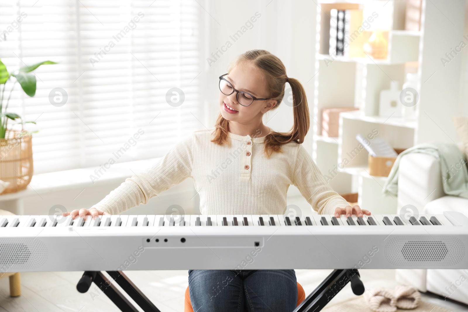 Photo of Cute girl playing synthesizer at home. Electronic musical instrument