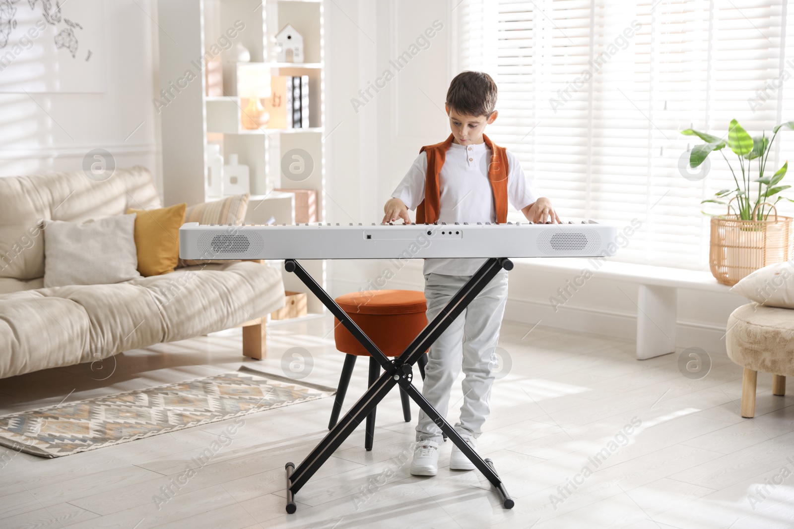 Photo of Cute boy playing synthesizer at home. Electronic musical instrument