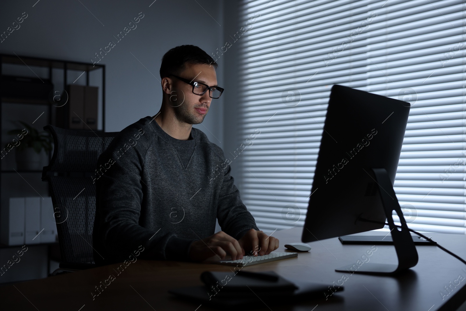 Photo of Programmer working on computer indoors at night