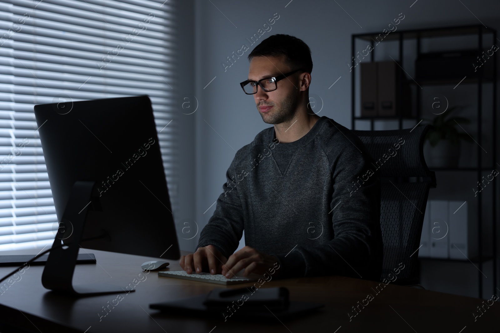 Photo of Programmer working on computer indoors at night