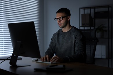 Photo of Programmer working on computer indoors at night