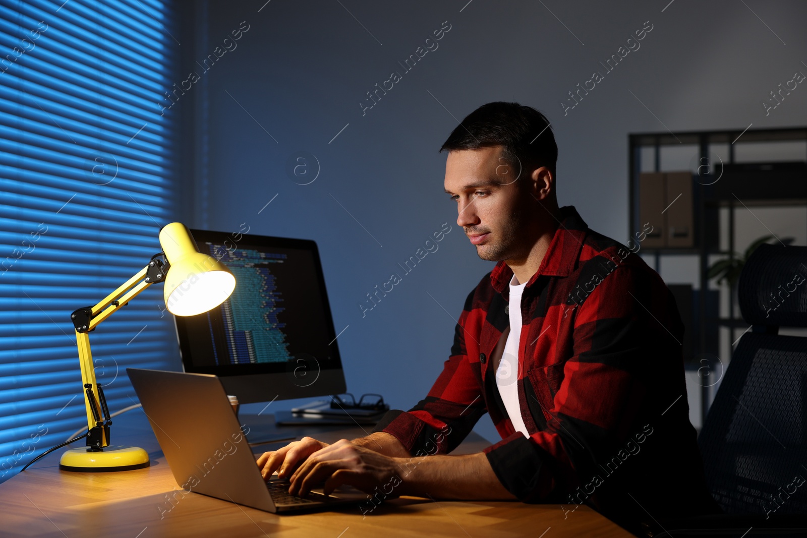 Photo of Programmer working on laptop indoors at night