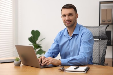 Photo of Programmer with laptop at wooden desk indoors