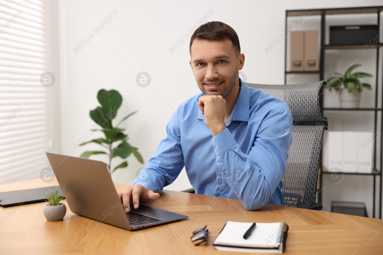 Photo of Programmer with laptop at wooden desk indoors