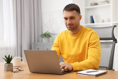 Photo of Programmer working on laptop at wooden desk indoors