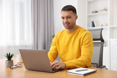 Photo of Programmer working on laptop at wooden desk indoors