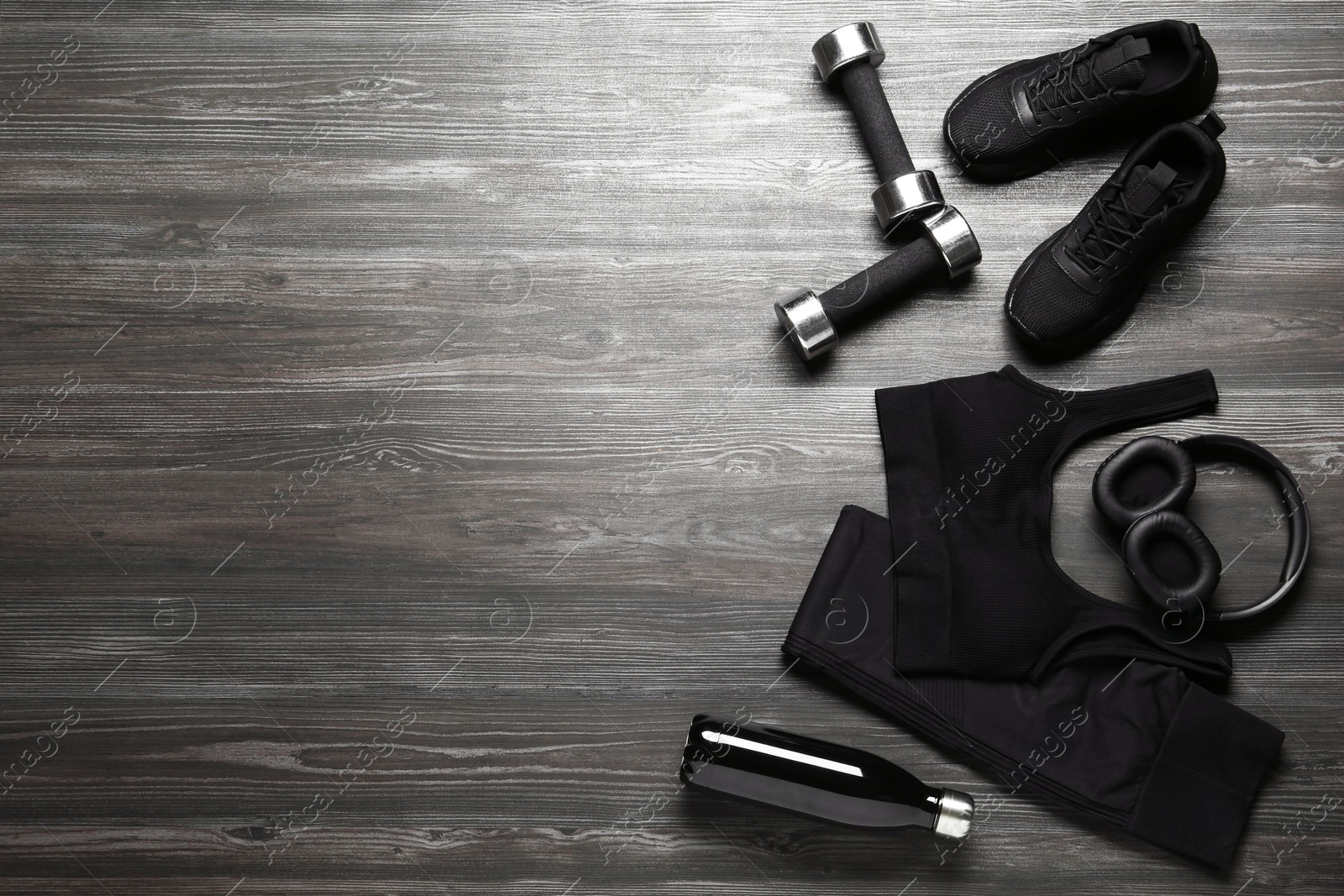 Photo of Flat lay composition with black sportswear and sneakers on wooden background, space for text