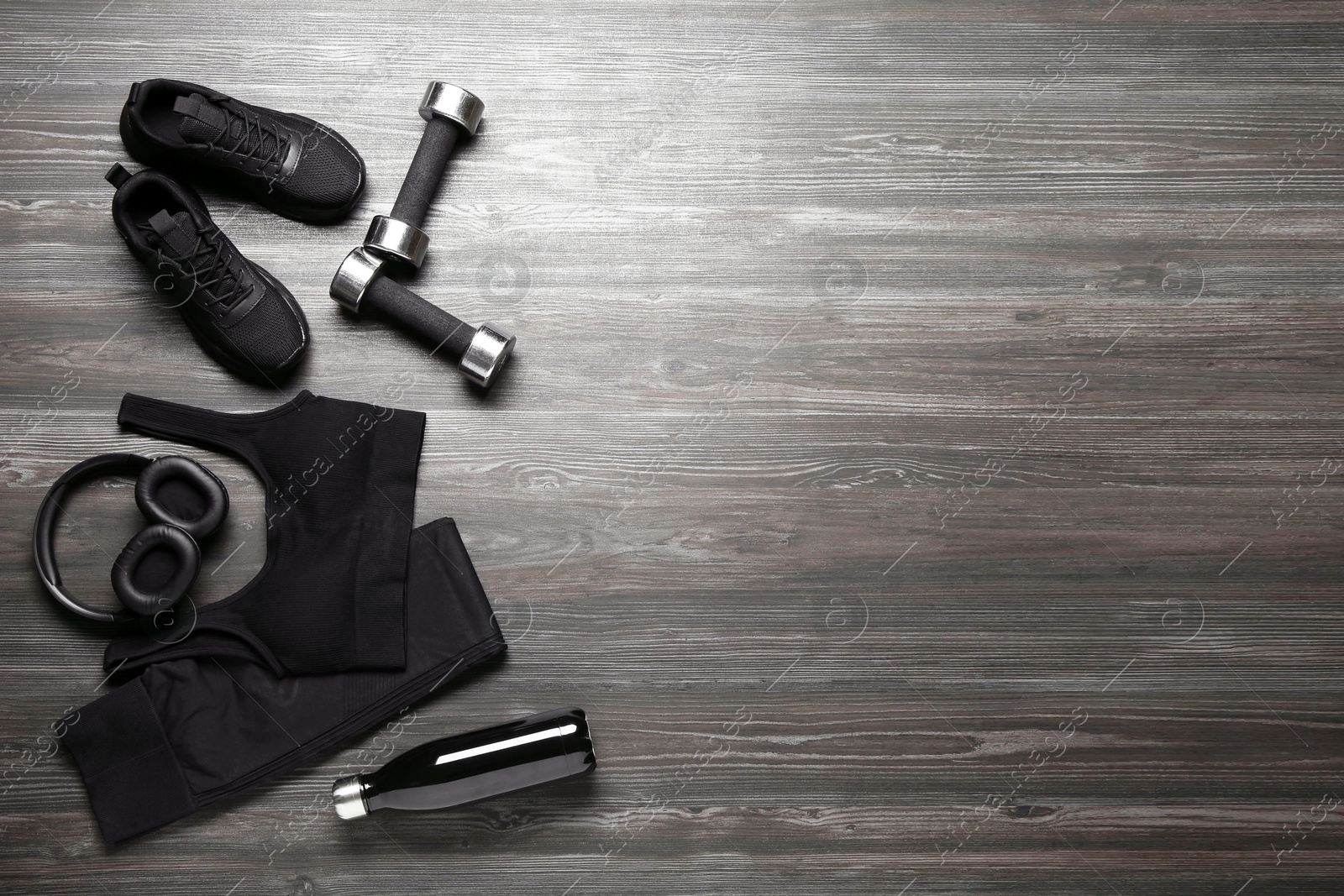 Photo of Flat lay composition with black sportswear and sneakers on wooden background, space for text