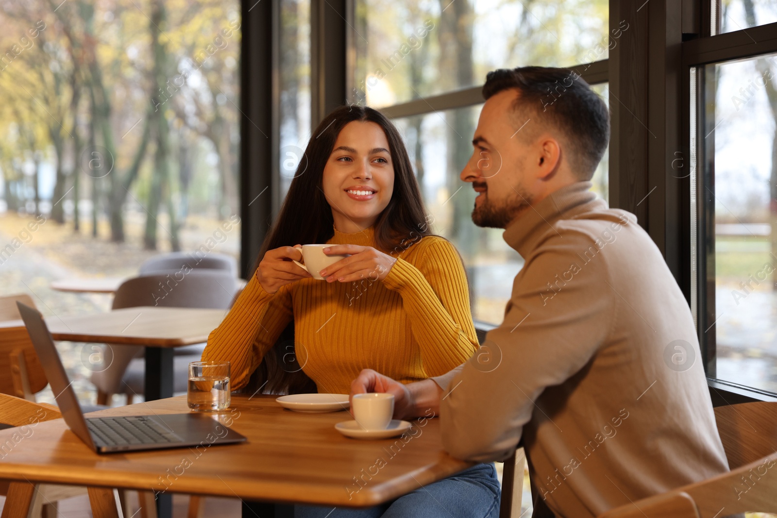 Photo of Colleagues with laptop working together at table in cafe