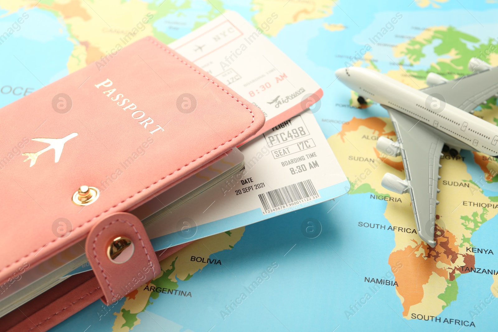 Photo of Passport with tickets and plane model on world map, closeup