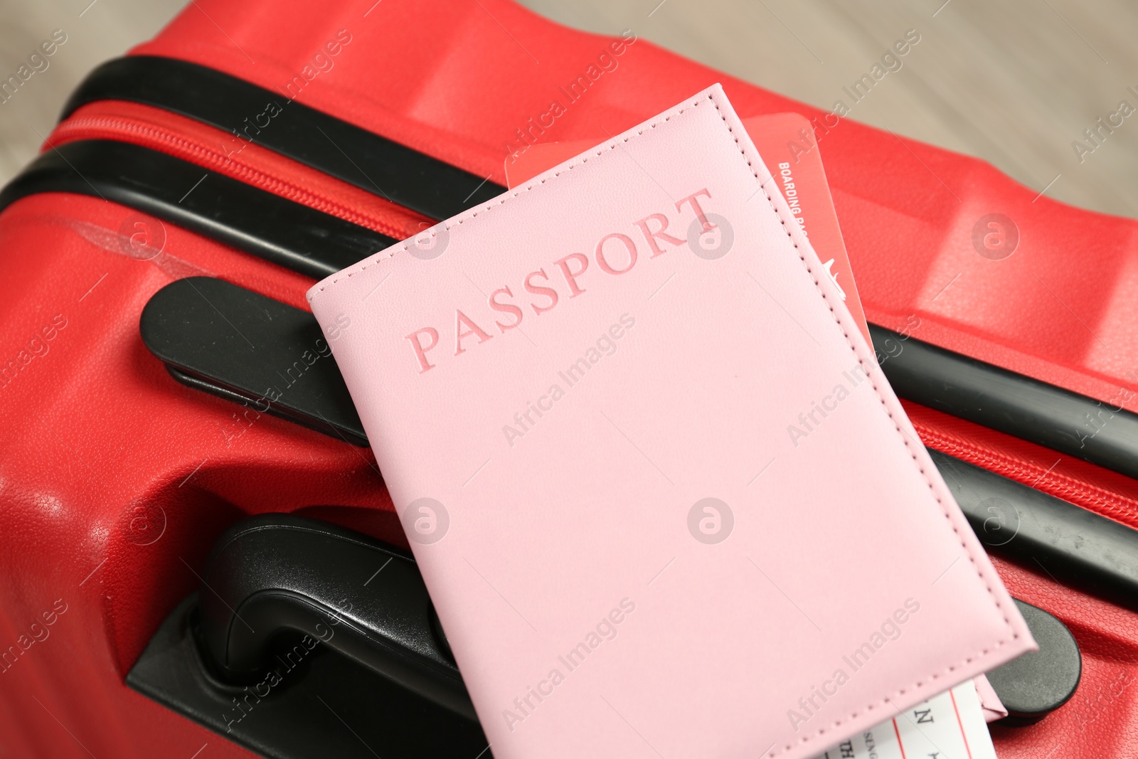 Photo of Passport with ticket on red suitcase, closeup