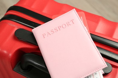 Photo of Passport with ticket on red suitcase, closeup