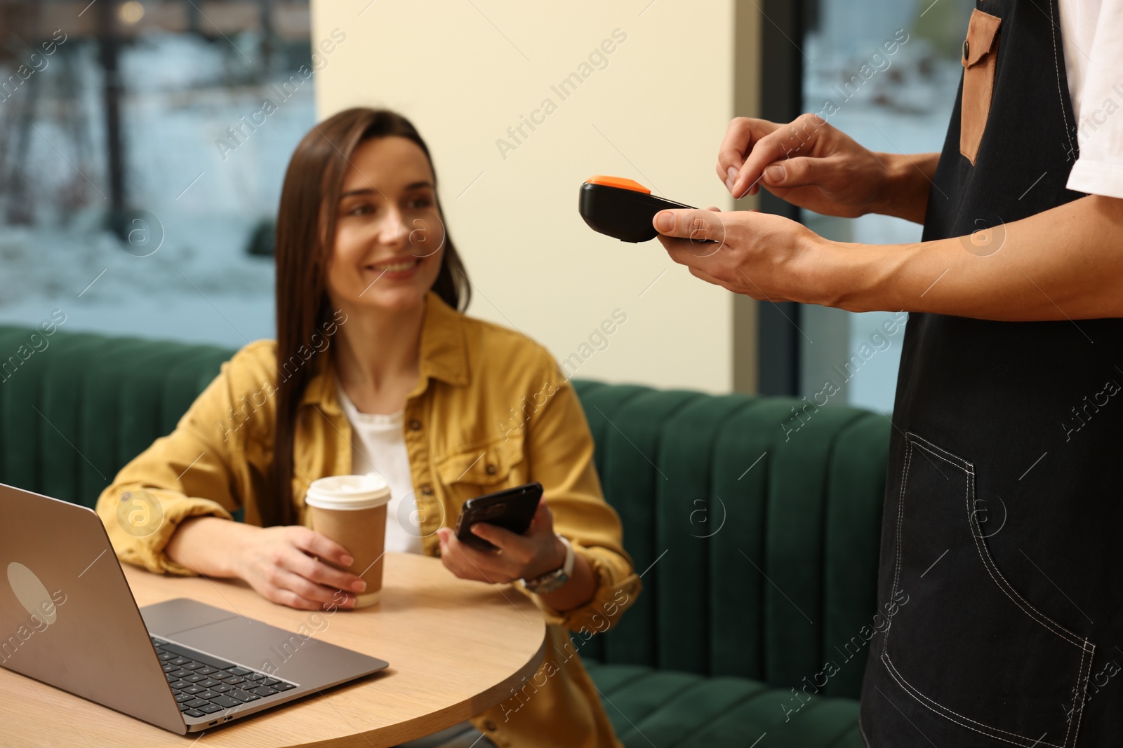 Photo of Waiter taking payment from client via terminal in cafe, selective focus