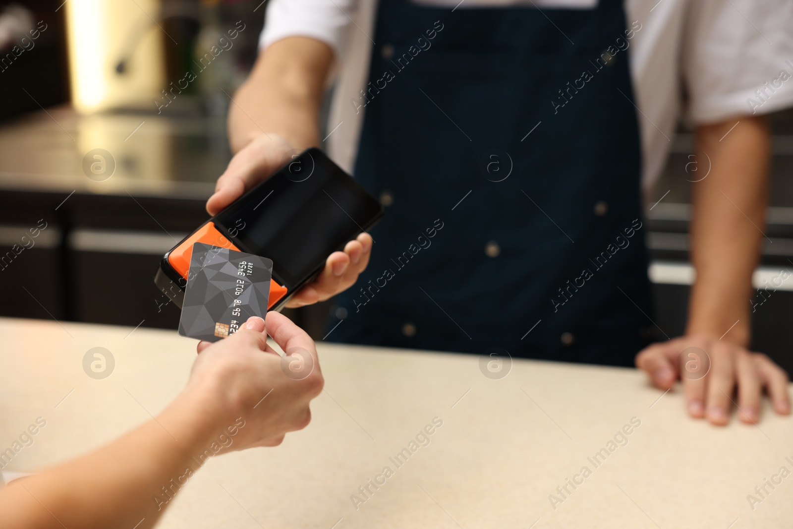 Photo of Woman paying with credit card via terminal in cafe, closeup