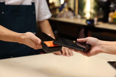 Photo of Woman paying with smartphone via terminal in cafe, closeup