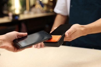 Photo of Woman paying with smartphone via terminal in cafe, closeup