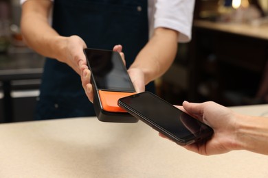 Photo of Woman paying with smartphone via terminal in cafe, closeup