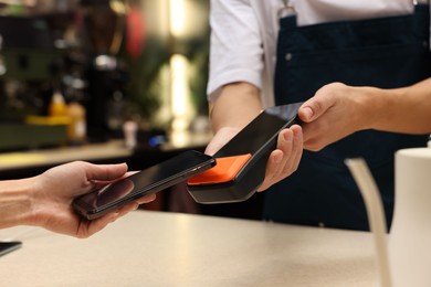 Photo of Woman paying with smartphone via terminal in cafe, closeup