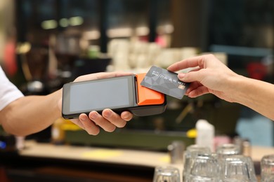 Photo of Woman paying with credit card via terminal in cafe, closeup