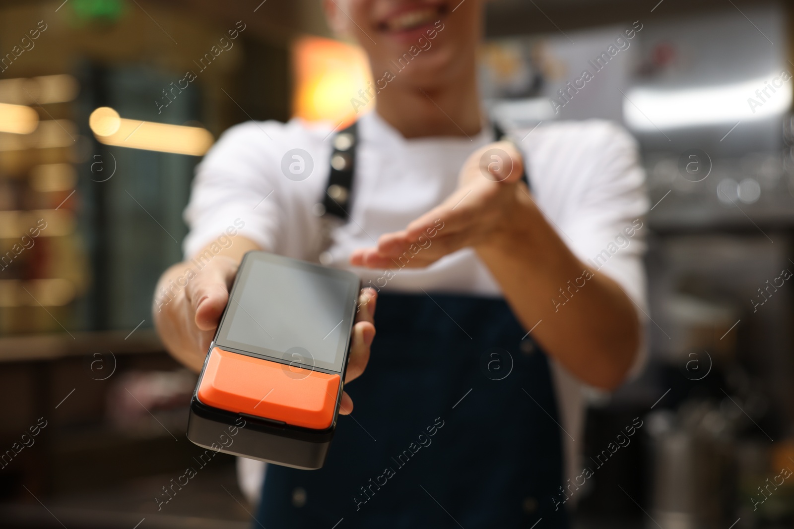 Photo of Cafe worker with payment terminal indoors, closeup