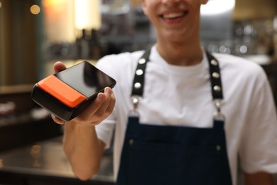 Photo of Cafe worker with payment terminal indoors, closeup