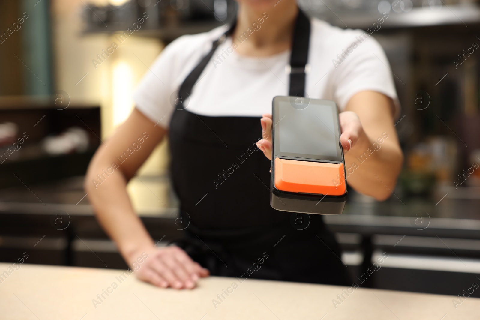 Photo of Cafe worker with payment terminal indoors, closeup