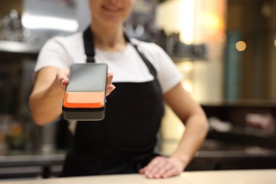 Photo of Cafe worker with payment terminal indoors, closeup