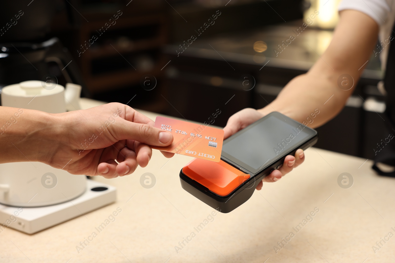 Photo of Man paying with credit card via terminal in cafe, closeup