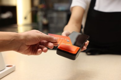 Photo of Man paying with credit card via terminal in cafe, closeup