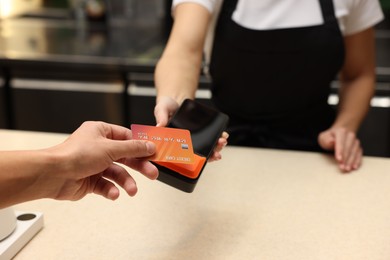 Photo of Man paying with credit card via terminal in cafe, closeup