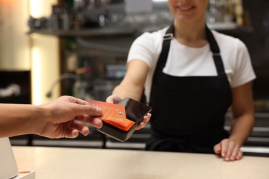 Photo of Man paying with credit card via terminal in cafe, closeup