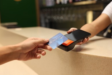 Photo of Man paying with credit card via terminal in cafe, closeup