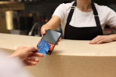 Photo of Man paying with credit card via terminal in cafe, closeup