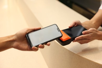 Photo of Man paying with smartphone via terminal in cafe, closeup