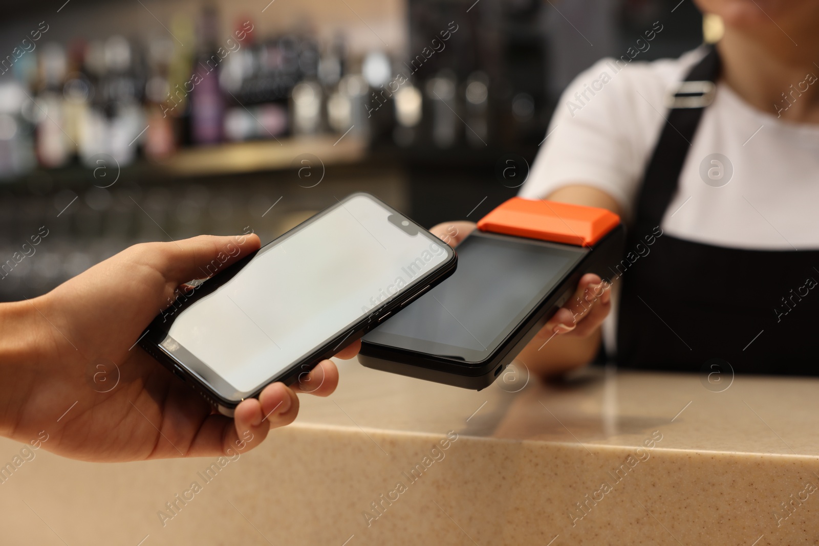 Photo of Man paying with smartphone via terminal in cafe, closeup