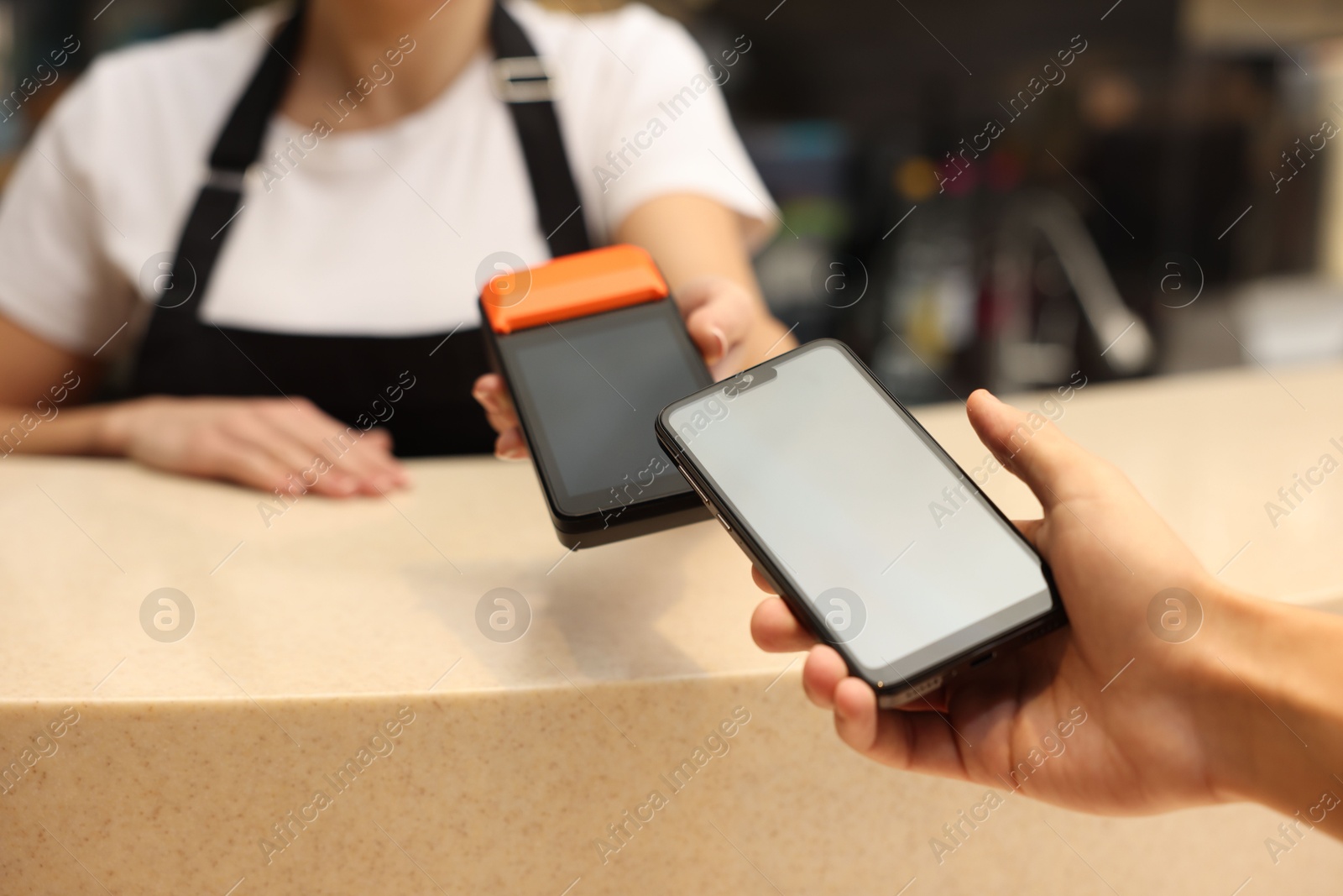 Photo of Man paying with smartphone via terminal in cafe, closeup