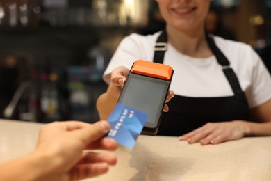 Photo of Man paying with credit card via terminal in cafe, closeup