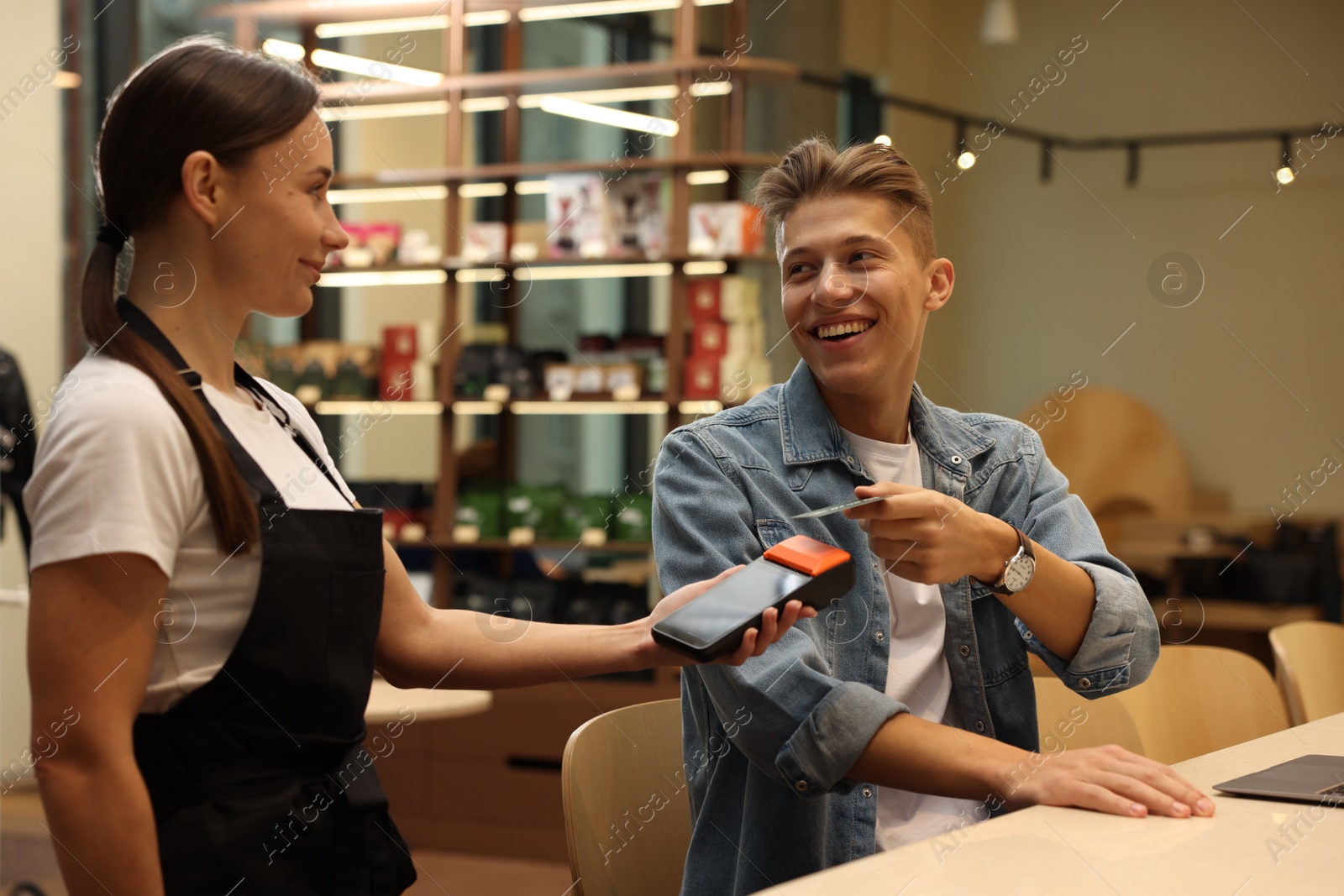 Photo of Man paying with credit card via terminal in cafe