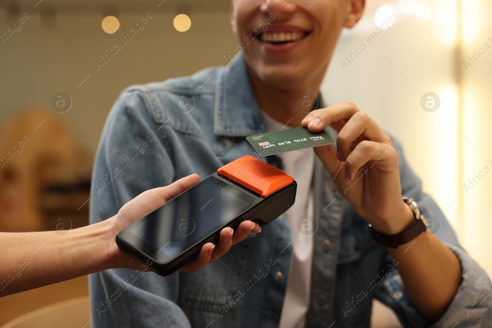 Photo of Man paying with credit card via terminal in cafe, closeup