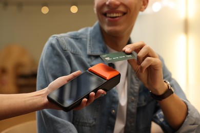 Photo of Man paying with credit card via terminal in cafe, closeup