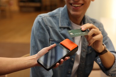 Photo of Man paying with credit card via terminal in cafe, closeup