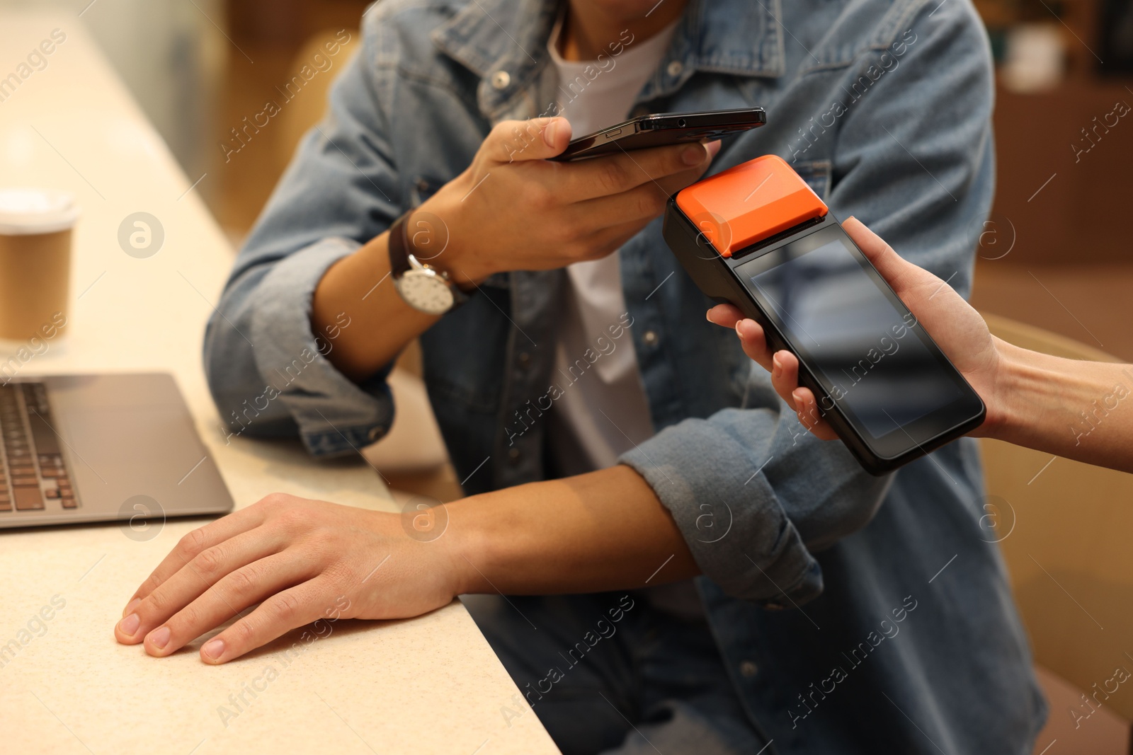 Photo of Man paying with smartphone via terminal in cafe, closeup