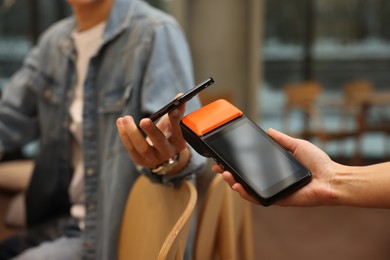 Photo of Man paying with smartphone via terminal in cafe, closeup