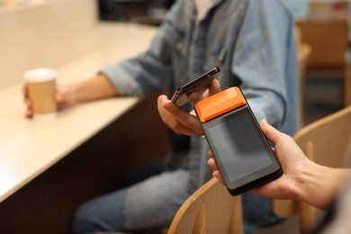 Photo of Man paying with smartphone via terminal in cafe, closeup