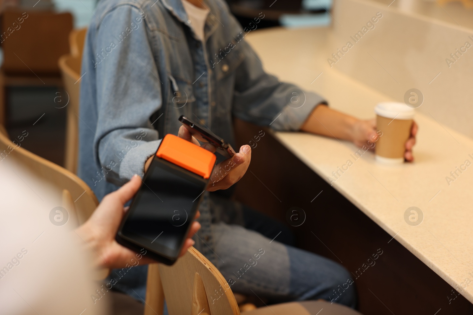 Photo of Man paying with smartphone via terminal in cafe, closeup