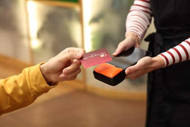 Photo of Man paying with credit card via terminal in cafe, closeup